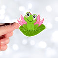 Load image into Gallery viewer, This image shows a hand holding the froggy on a lily pad sticker.