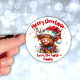Load image into Gallery viewer, This image shows a hand holding the Personalized Holiday Stickers - Highland Cow Christmas.