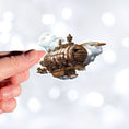 Load image into Gallery viewer, This image shows a hand holding the Steampunk Airship 1 Die-Cut Sticker