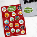 Load image into Gallery viewer, Our Around the World sticker sheet collection has sticker images of iconic travel destinations! This sheet has a red background with 18 different stickers. This image shows the sticker sheet next to an open laptop with the sticker sheet header saying "Around the World" in white on a green background applied below the keyboard.