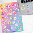 Load image into Gallery viewer, This sticker sheet is filled with stickers of princess's, rainbows, unicorns, and even a frog to kiss (will he turn into a prince?)! This image shows the sticker sheet next to an open laptop with stickers of a princely frog, a princess in a blue gown, and a pink star, below the keyboard.