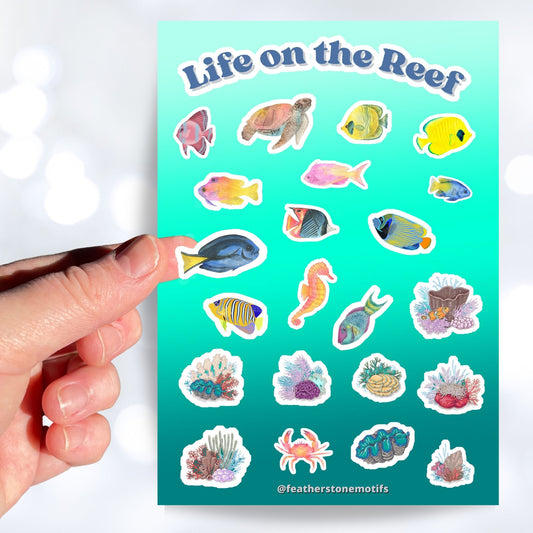 Teaming with sea life, this sticker sheet is filled with sticker images of fish, sea turtles, and coral! Take the reef with you anywhere with these beautiful stickers. This image shows a hand holding a sticker of a blue tang above the sticker sheet.