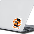 Load image into Gallery viewer, Grab your favorite beverage and relax under the palm trees! This individual die-cut sticker features two palm trees and an umbrella drink in a coconut shell, on an orange and white gradient background, with the word "Relaxing" below. This image shows the relaxing sticker on the back of an open laptop.