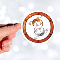 Load image into Gallery viewer, This round individual die-cut sticker features a rusty ring with screws on a white background with two mechanical geckos, one silver and one rust colored, in a yin-yang configuration. This image shows a hand holding the steampunk geckos sticker.