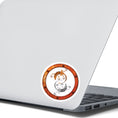 Load image into Gallery viewer, This round individual die-cut sticker features a rusty ring with screws on a white background with two mechanical geckos, one silver and one rust colored, in a yin-yang configuration. This image shows the steampunk geckos sticker on the back of an open laptop.