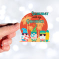 Load image into Gallery viewer, Who doesn't want to chill with their gnomies in the summer? This individual die-cut sticker features three gnome friends who are ready for the beach. They're standing in front of a setting sun silhouetting palm trees. Enjoy! This image shows a hand holding the Summer with my Gnomies sticker.