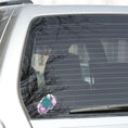 Load image into Gallery viewer, This individual die-cut sticker features a green tribal style turtle on a gray and pink cloudy background. This image shows the turtle sticker on the back window of a car.