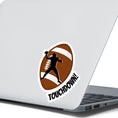 Load image into Gallery viewer, This individual die-cut sticker features the silhouette of a football (American) player about to pass the ball, on a football background, with the word "Touchdown!" on the lower right side. This image shows the touchdown sticker on the back of an open laptop.