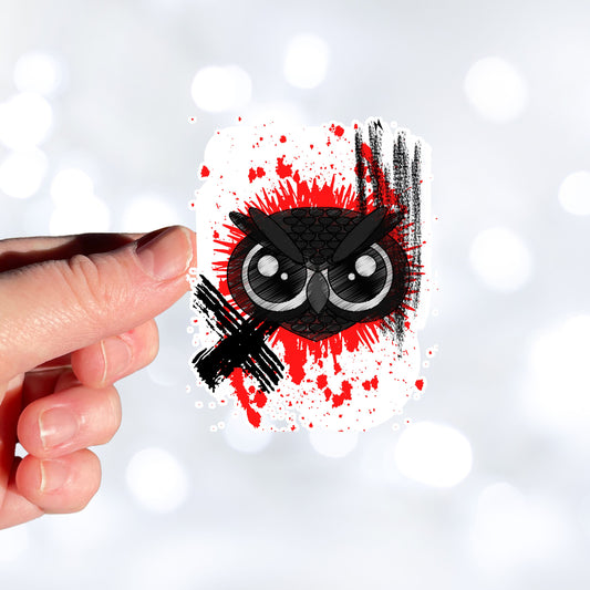 Trash Polka uses red, black, and white with a combination of abstract, surrealistic, and realistic images, and this individual die-cut sticker features a black owl face on a red and white background. This image shows a hand holding the trash polka owl sticker.