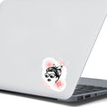 Load image into Gallery viewer, Trash Polka uses red, black, and white with a combination of abstract, surrealistic, and realistic images, and this individual die-cut sticker features a woman wearing sunglasses with her hair tied up on a white background with red swirls. This image shows the trash polka woman sticker on the back of an open laptop.