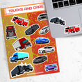 Load image into Gallery viewer, This sticker sheet has a collection of truck and car stickers; perfect for kids and adults who like their four wheel friends! This sheet has five different truck stickers and seven different car stickers on an orange and yellow background. This image shows the sticker sheet next to an open laptop with stickers of a semi truck and a fire truck applied below the keyboard.