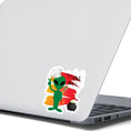 Load image into Gallery viewer, I wouldn't trust this space alien! This individual die-cut sticker features a green space alien flashing a peace sign, but wearing a chefs hat and trying to hide a wooden spoon, with a boiling pot behind, all on an orange background with the words "Trust Me!" in the upper right corner. This image shows the trust me alien sticker on the back of an open laptop.