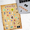 Load image into Gallery viewer, Yo Ho Ho, a Pirate's Life for Me! This sticker sheet is a treasure-worthy find for any pirate with images of the Jolly Roger, treasure, maps, pirates, and a pirate ship. This image is of the sticker sheet next to a laptop with stickers of a pirate's flag with skull and crossbones, the sticker sheet header reading Yo Ho Ho, and a skull and crossed swords, applied below the keyboard.