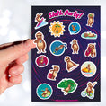 Load image into Gallery viewer, Sloth's on Bikes. Sloth's scuba diving. Sloth's relaxing. This sticker sheet is full of sticker images of sloth's doing all kinds of fun things! This image shows a hand holding a sticker of a sloth with a cup of coffee above the sticker sheet.