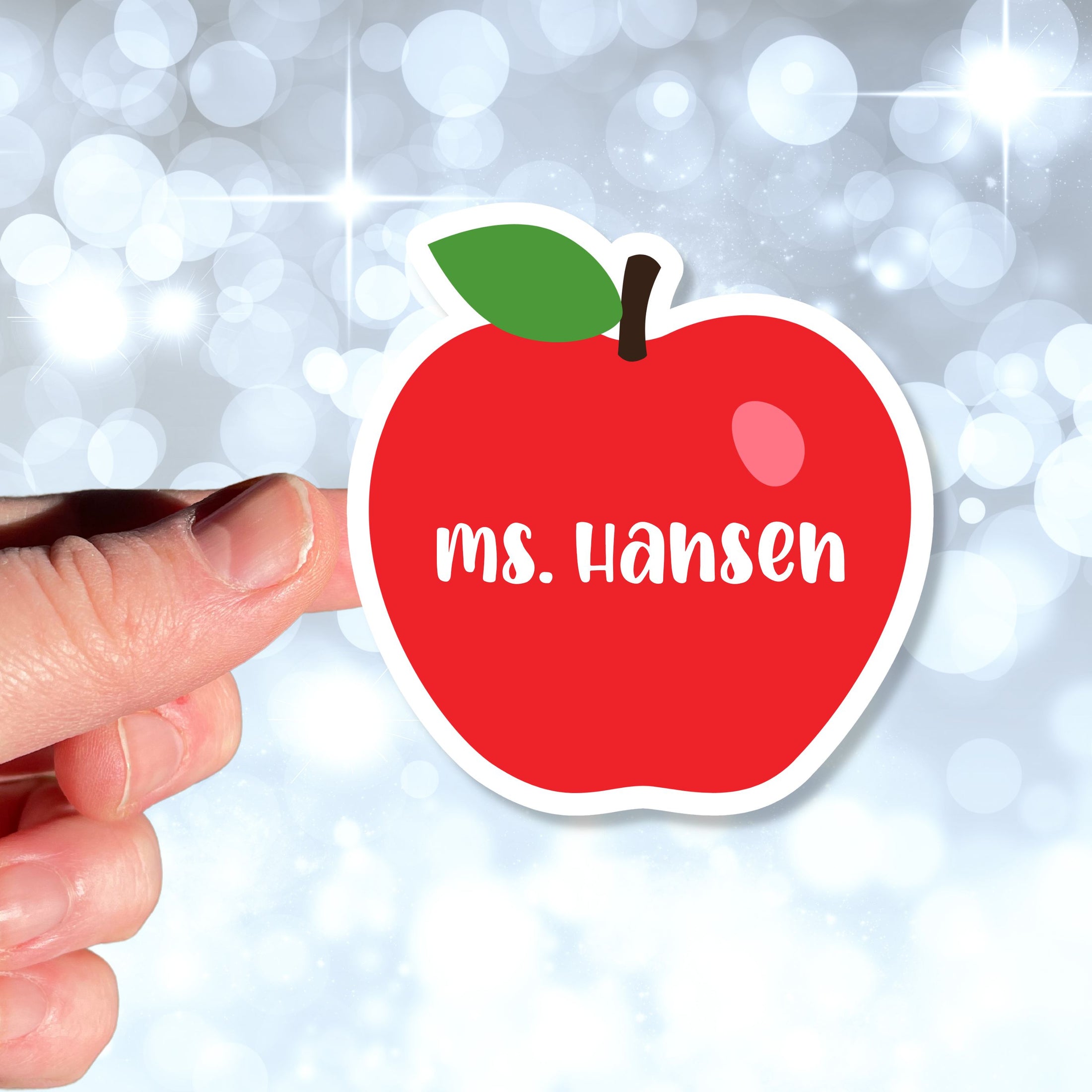 This image shows a hand holding the personalized school sticker.