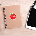 Load image into Gallery viewer, This image shows the personalized school sticker on a notebook next to a smartphone and pen.
