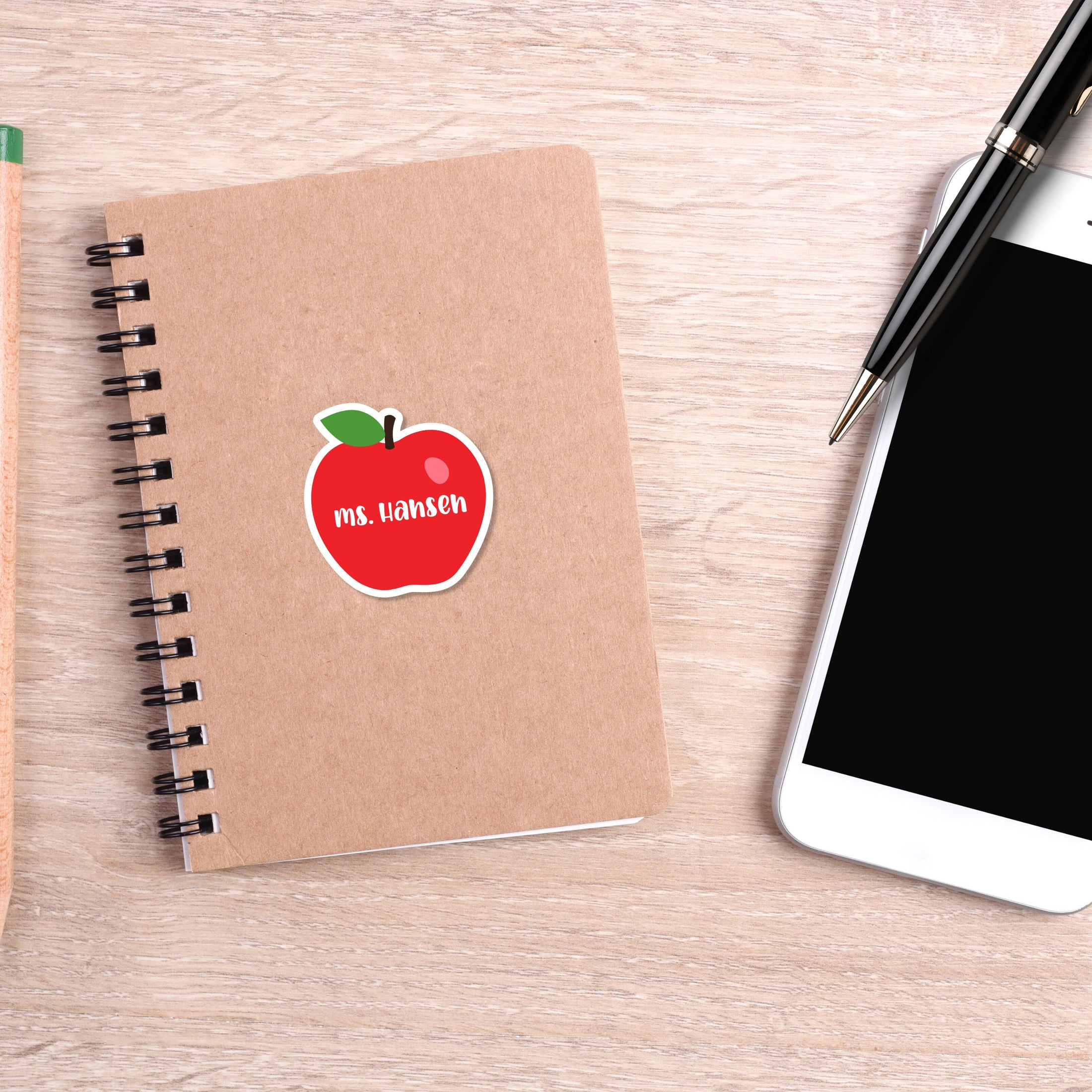 This image shows the personalized school sticker on a notebook next to a smartphone and pen.