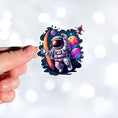 Load image into Gallery viewer, This image shows a hand holding the astronaut spacewalk sticker.

