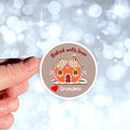 Load image into Gallery viewer,  This image shows the personalized holiday sticker being held on one finger over a background of bubbles.
