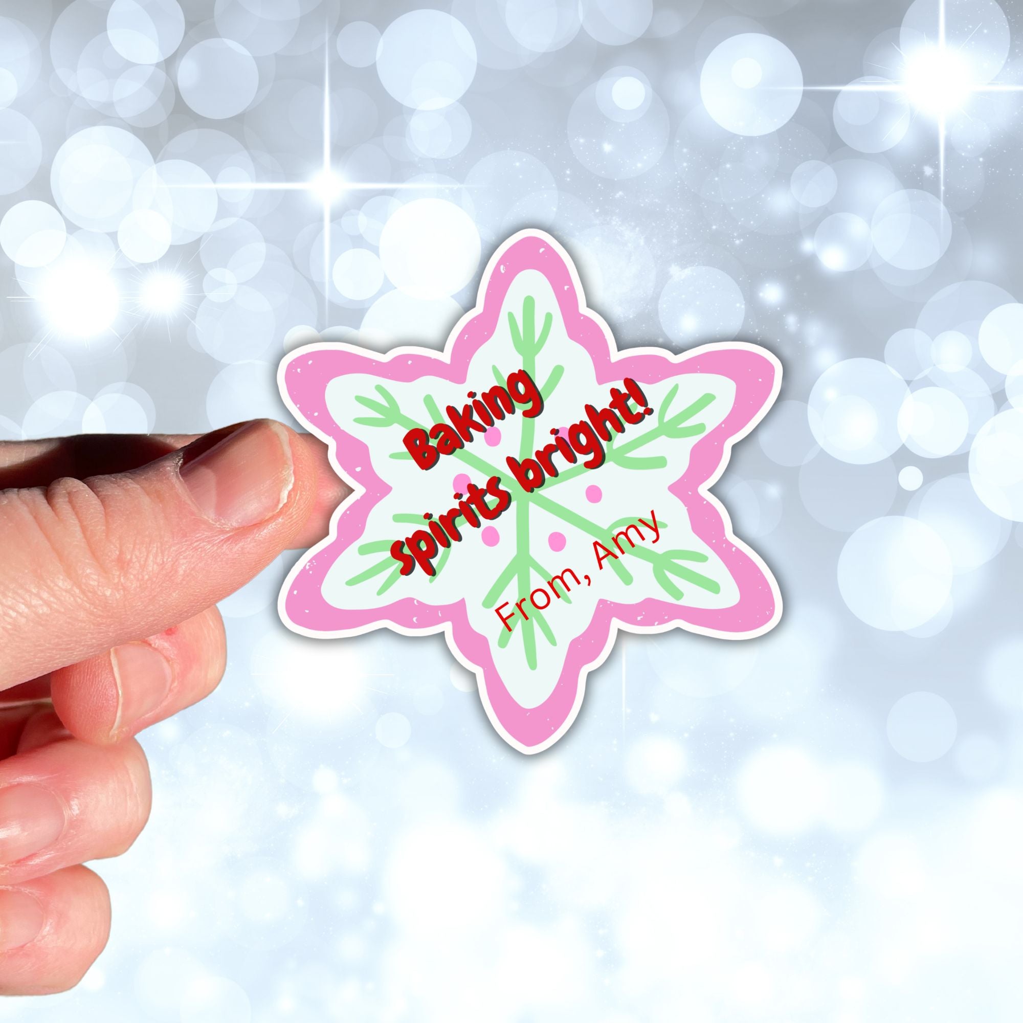 This image shows a hand holding the Personalized Holiday Stickers - Baking Spirits Bright.