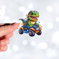 Load image into Gallery viewer, This image shows a hand holding the dino on ATV sticker.
