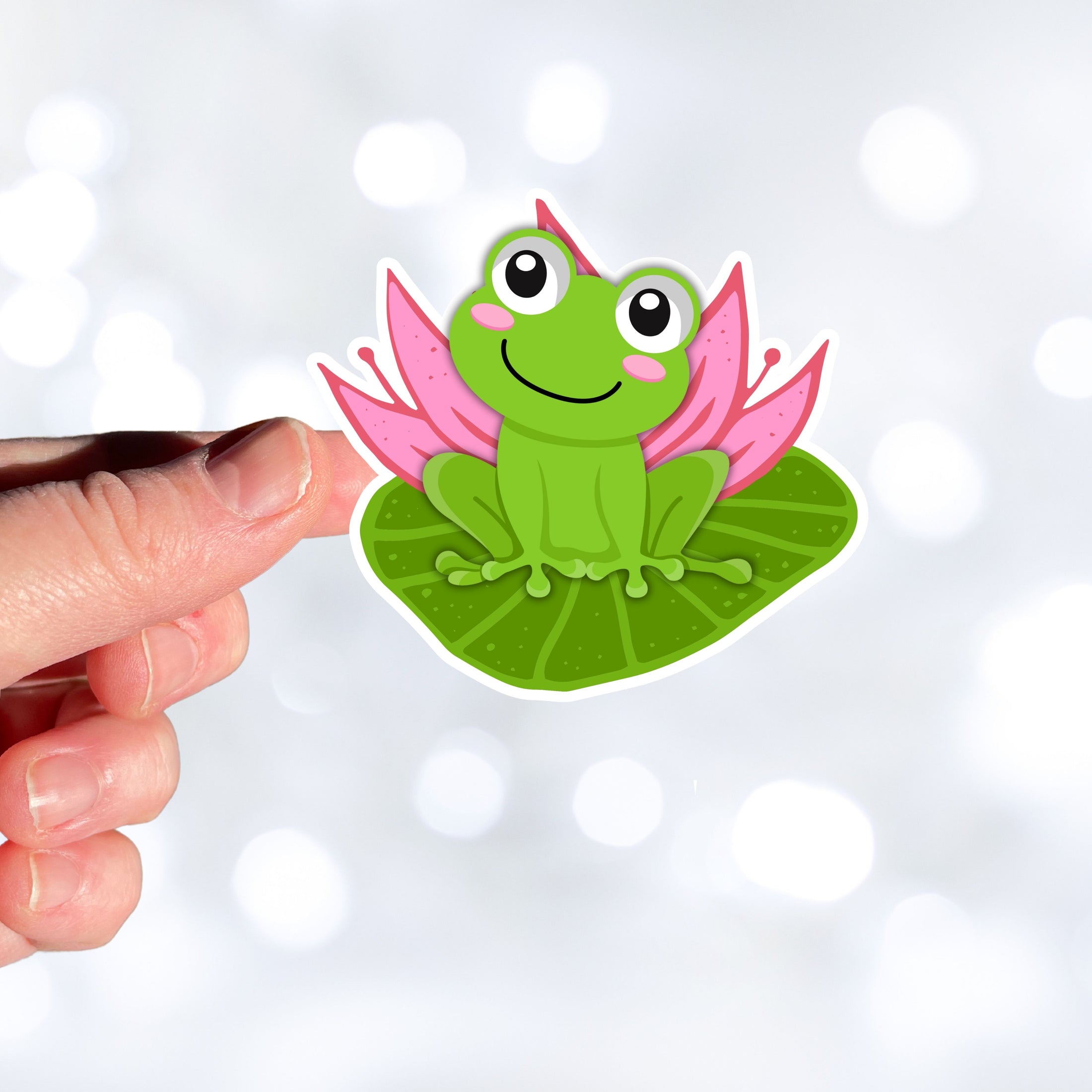 This image shows a hand holding the froggy on a lily pad sticker.