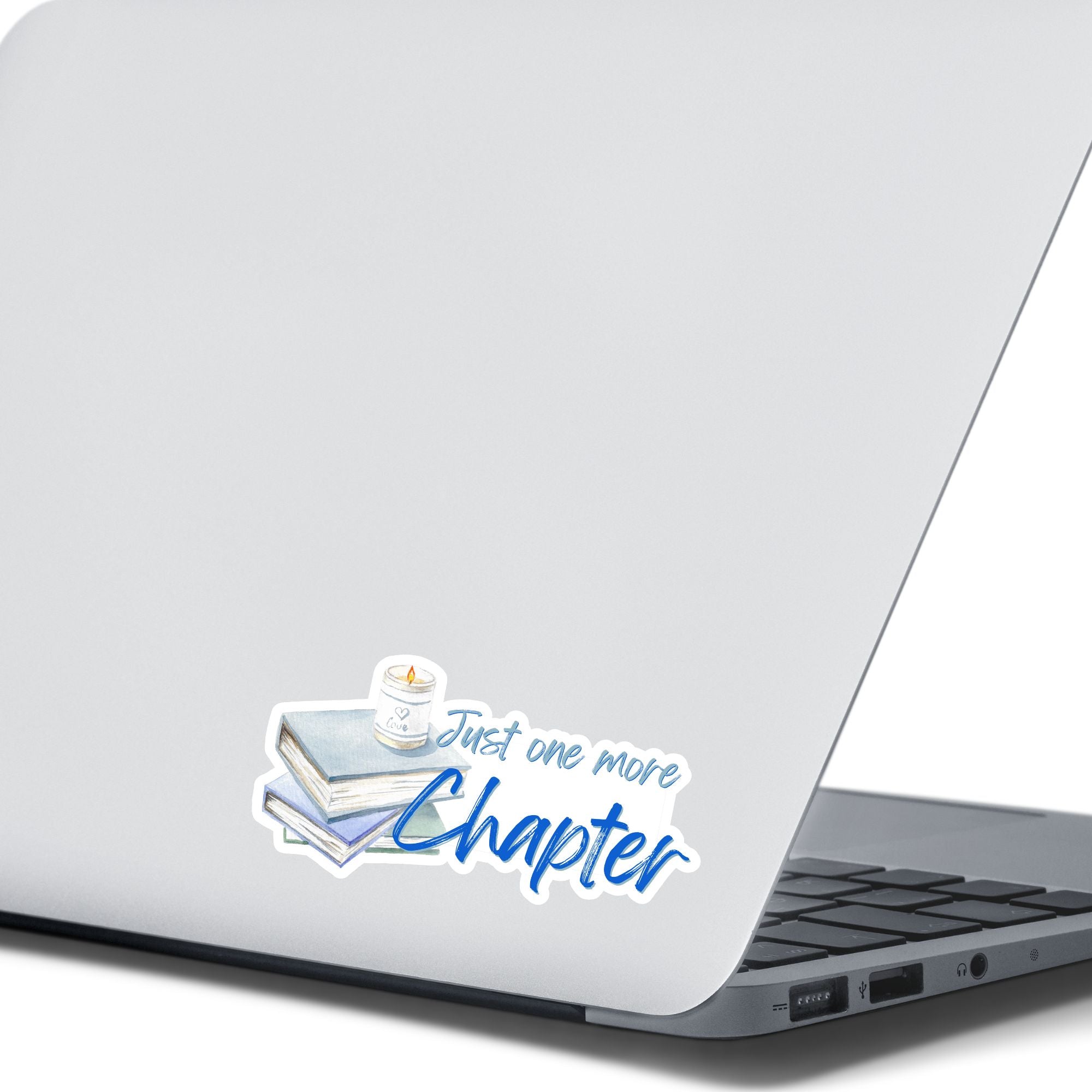 Love to read? If so then you know that there's always time for one more chapter! This individual die-cut sticker features a stack of books with a candle on top, and the words "Just One More Chapter", all in blue and gray on white. Enjoy your reading! This image shows the Just One More Sticker on the back of an open laptop.