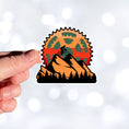 Load image into Gallery viewer, This image shows a hand holding the Keep Biking - Mountain Die-Cut Sticker.
