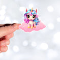 Load image into Gallery viewer, This image shows a hand holding the pink chibi unicorn sticker.
