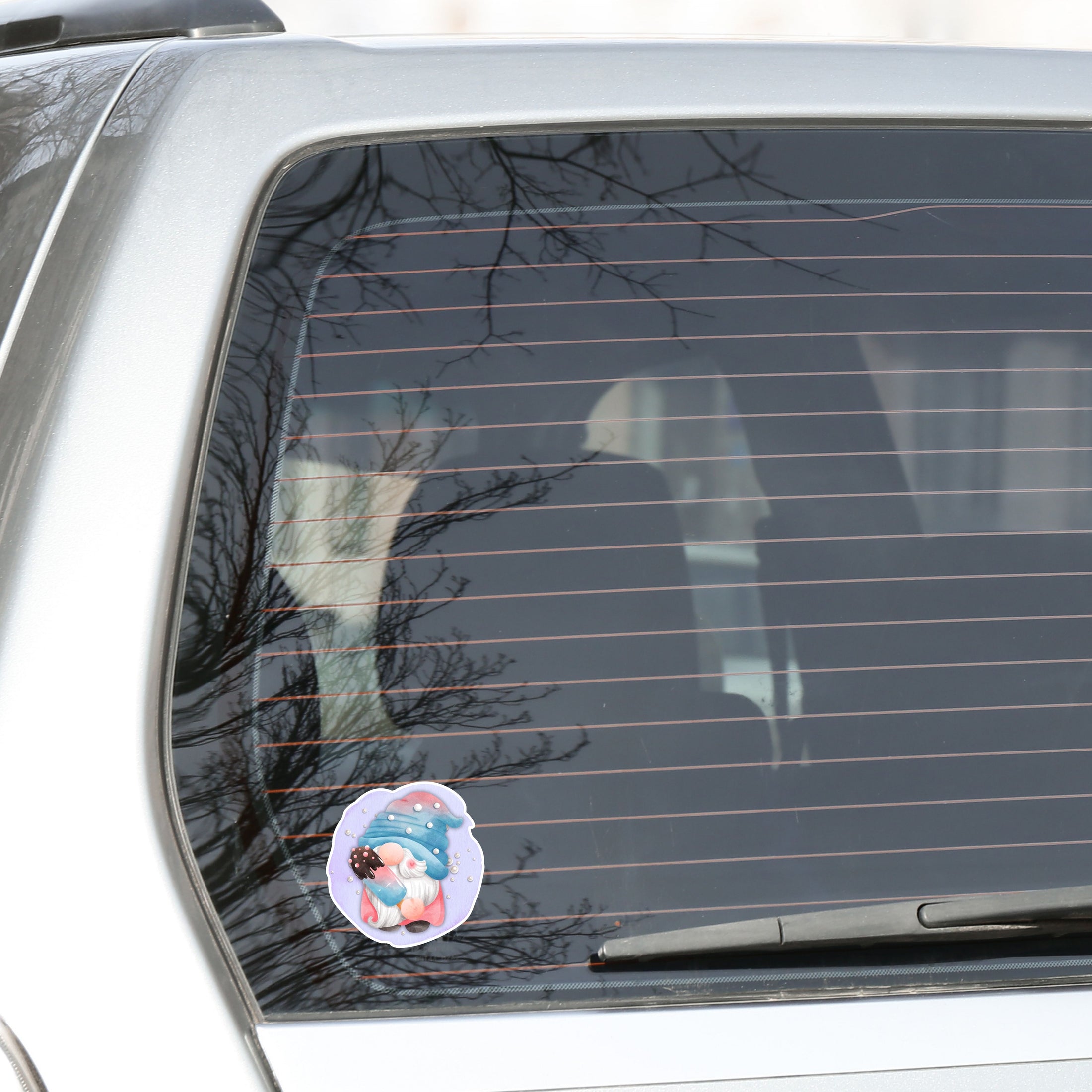 This image shows the gnome with a popsicle on the back window of a car.