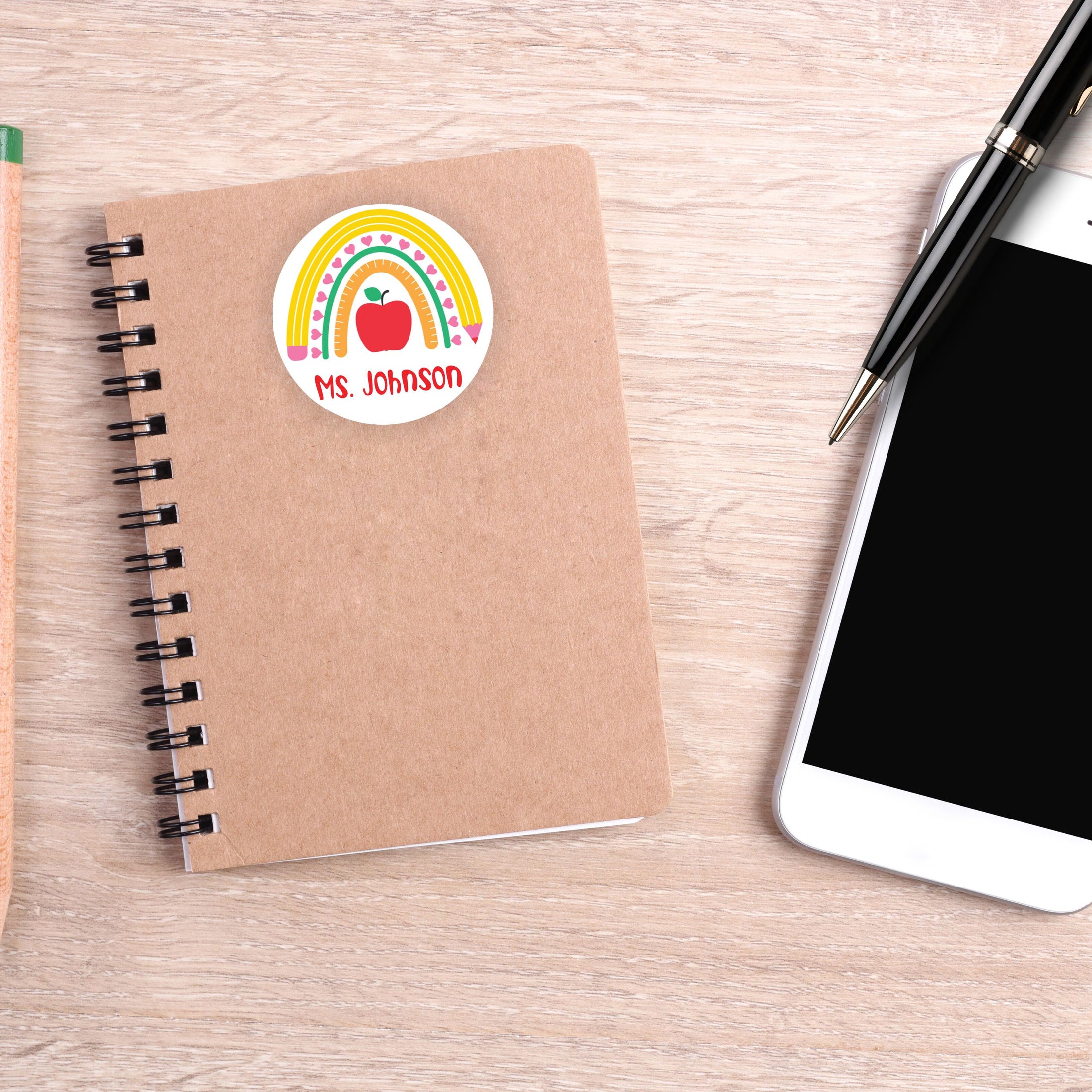 This image shows the personalized school sticker on a notebook next to a smartphone and pen.