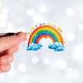 Load image into Gallery viewer, This image shows a hand holding the rainbow and hearts sticker.
