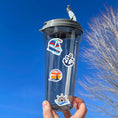 Load image into Gallery viewer, This image shows a water bottle with some of the Let's Sail Away stickers applied.
