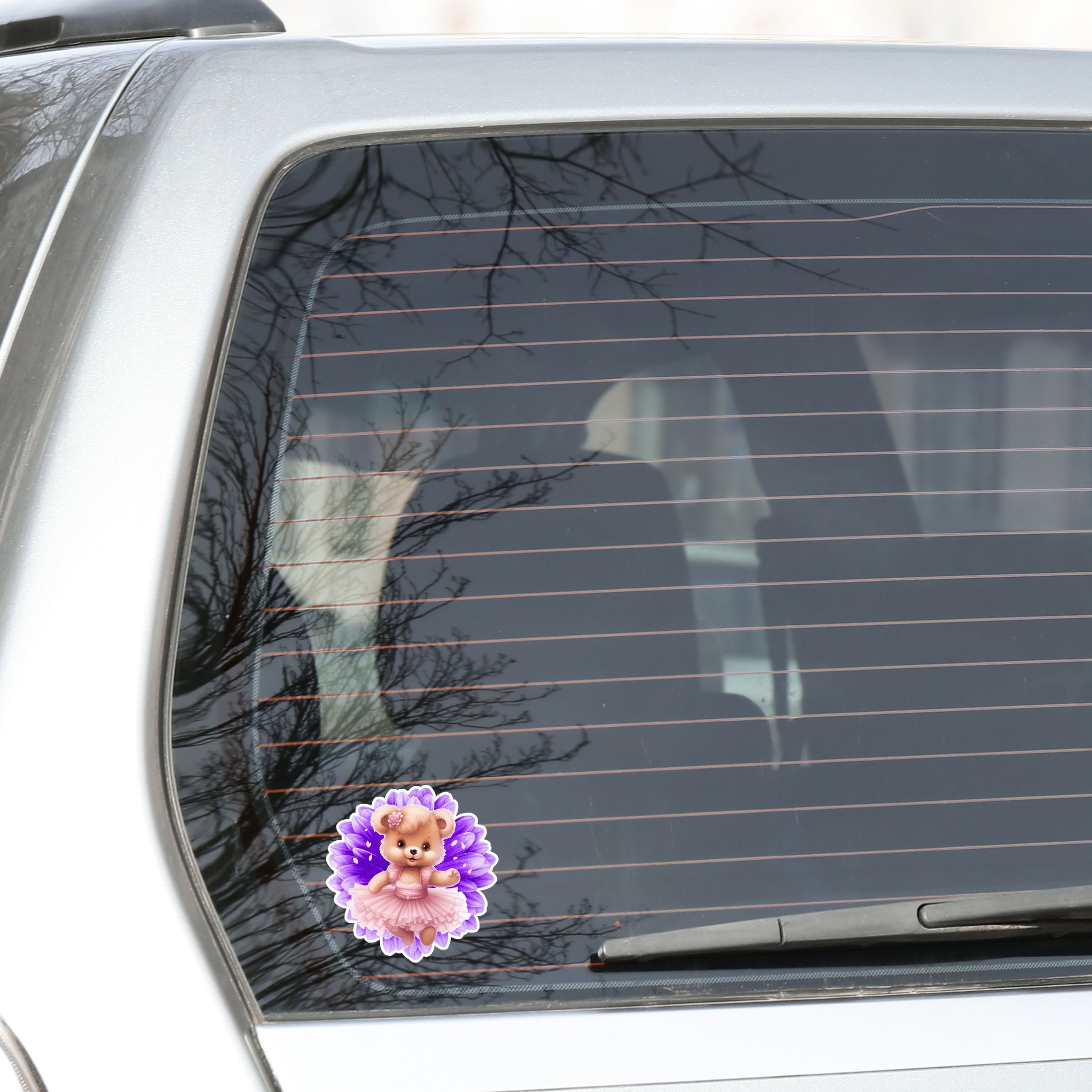 This image shows the teddy bear on purple sticker on the back window of a car.