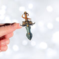 Load image into Gallery viewer, This image shows a hand holding the Pirate Dagger Die-Cut Sticker.
