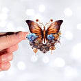 Load image into Gallery viewer, This image shows a hand holding the Steampunk Butterfly 2 Die-Cut Sticker.
