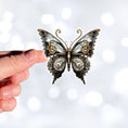 Load image into Gallery viewer, This image shows a hand holding the Steampunk Butterfly 3 Die-Cut Sticker.
