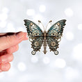 Load image into Gallery viewer, This image shows a hand holding the Steampunk Butterfly 4 Die-Cut Sticker.
