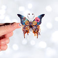 Load image into Gallery viewer, This image shows a hand holding the Steampunk Butterfly 6 Die-Cut Sticker.
