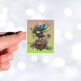 Load image into Gallery viewer, This image shows a hand holding the steampunk fantasy flower sticker.
