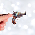 Load image into Gallery viewer, This image shows a hand holding the Pirate Steampunk Pistol 1 Die-Cut Sticker.
