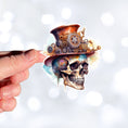 Load image into Gallery viewer, This image shows a hand holding the Steampunk Skull 1 Die-Cut Sticker.
