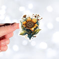 Load image into Gallery viewer, This image shows a hand holding the steampunk sunflower sticker.
