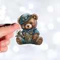 Load image into Gallery viewer, This image shows the steampunk teddy sticker on a finger.
