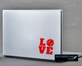 Load image into Gallery viewer, Love baseball? Then show it with this baseball love square vinyl decal! Available in 4 sizes and 10 colors, these vinyl decals make great gifts for everyone. This image shows the baseball love square decal on the back of an open laptop. 
