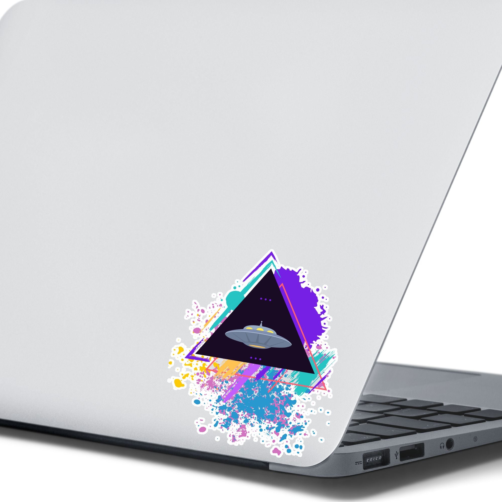 UFO alert! This individual die-cut sticker features an alien spaceship, UFO, on a black triangle background with pastel paint splatters behind. This image shows the UFO sticker on the back of an open laptop.