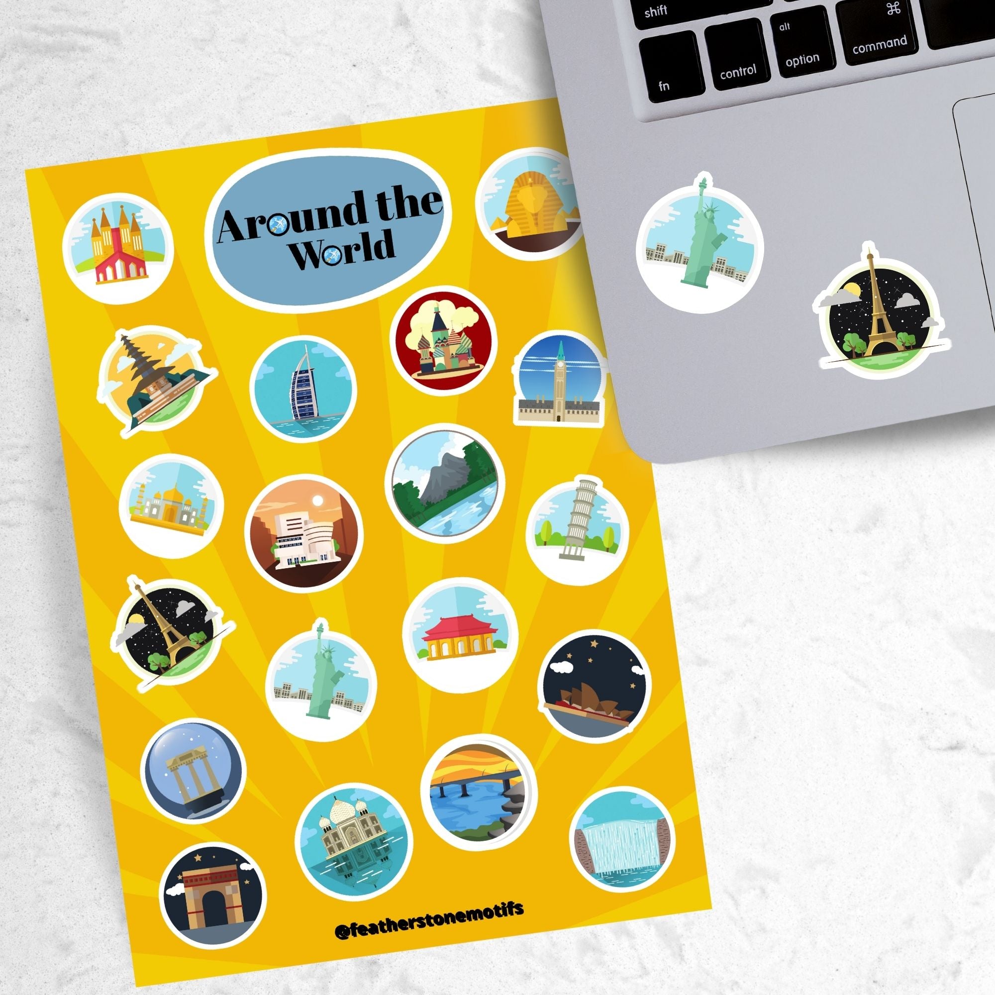 Our Around the World sticker sheet collection has sticker images of iconic travel destinations! This sheet has a yellow background with 20 different stickers. This image shows the sticker sheet next to an open laptop with stickers of the Statue of Liberty and the Eifel Tower applied below the keyboard.