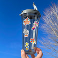 Load image into Gallery viewer, Who doesn't love going to the carnival? This sheet has stickers showing the big top, clowns, animals, and of course your favorite foods like hotdogs and cotton candy.  This is an image of a water bottle with stickers on it.
