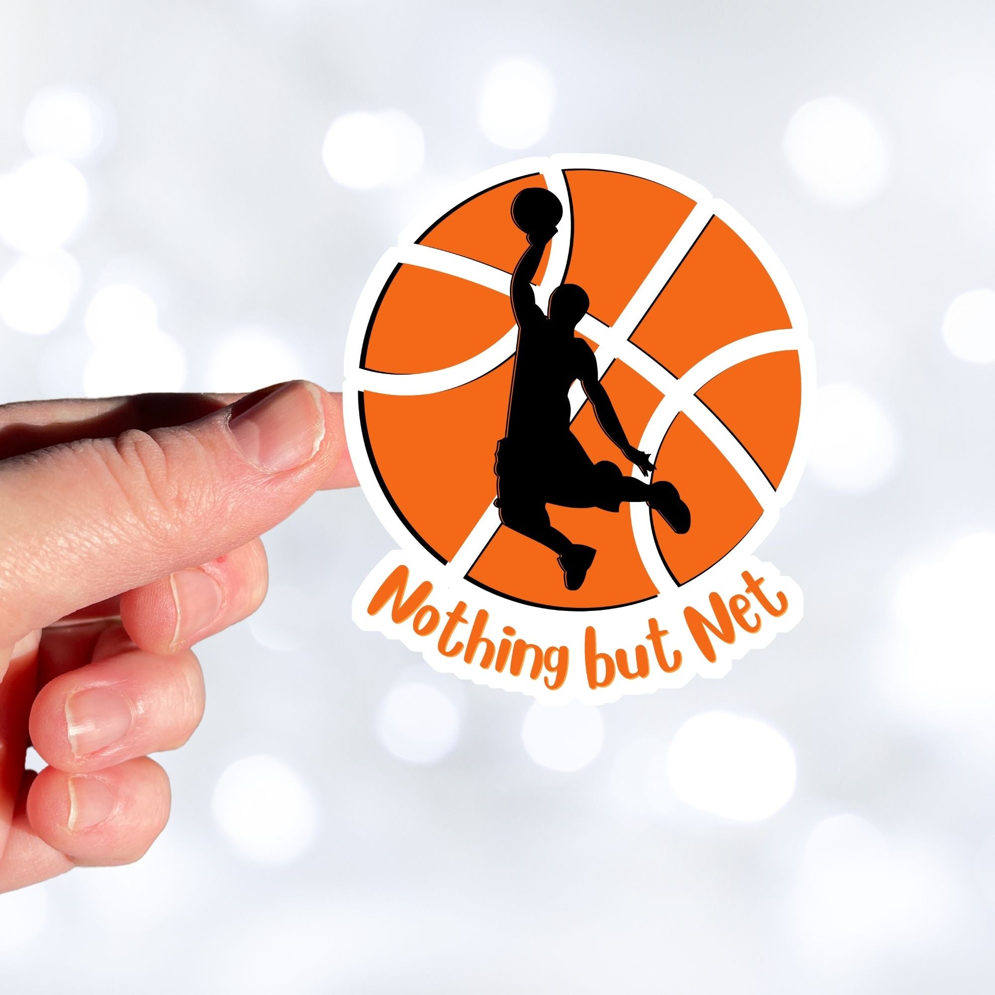 Dunk that basketball! This individual die cut sticker features a silhouette of someone about to dunk a ball, on a basketball background, with the words "Nothing but Net" at the bottom.  This image shows a hand holding the basketball sticker.