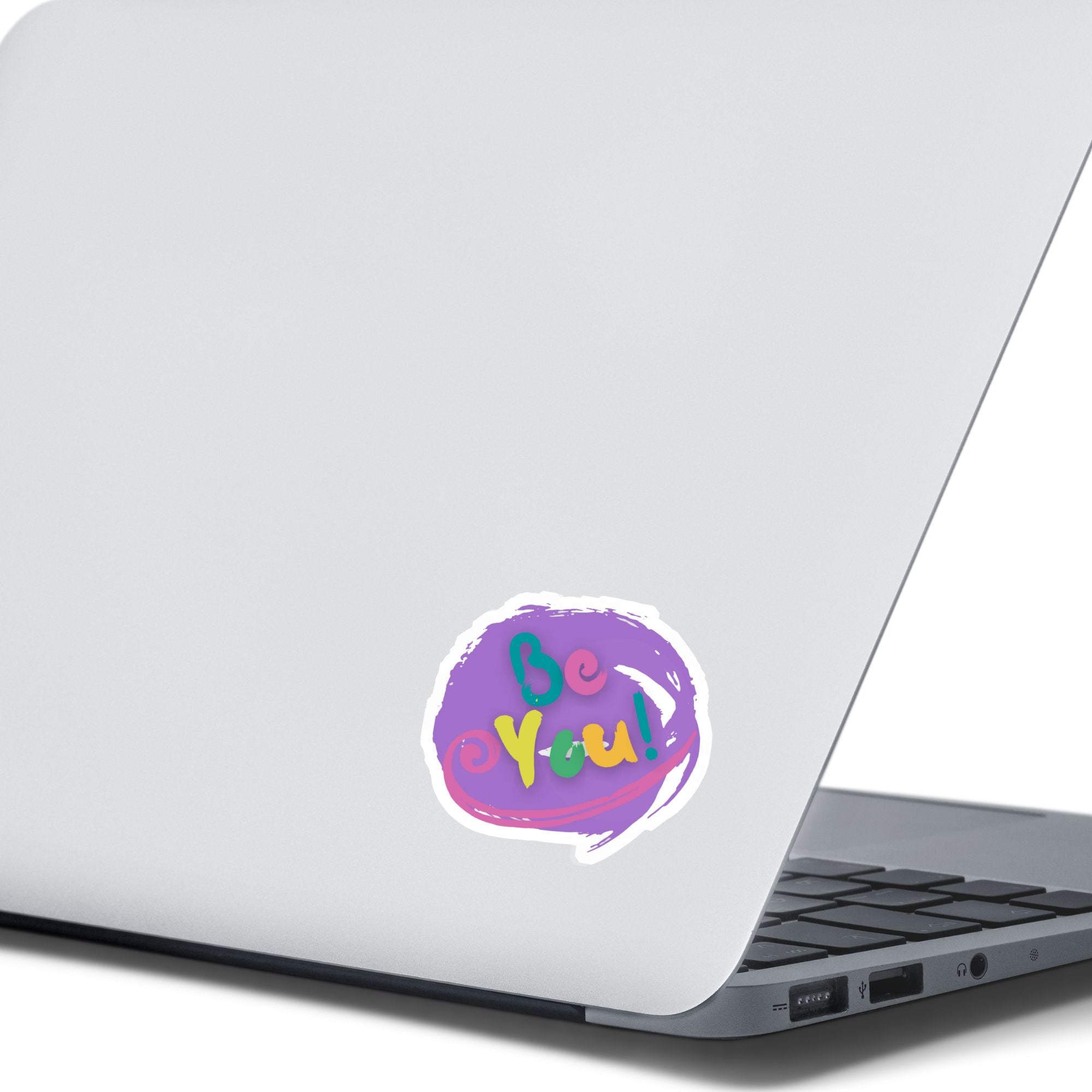 Be You - words to live by! This individual die-cut sticker features "Be You" in multiple pastel colors on a lavender background. This image shows the Be You! sticker on the back of an open laptop.